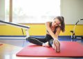 Woman in Black Sports Bra and Black Legging Sitting on Red Yoga Mat