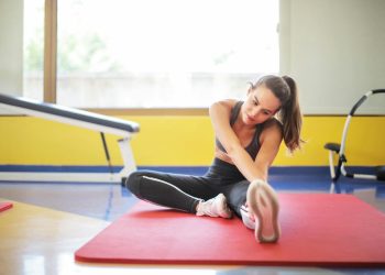 Woman in Black Sports Bra and Black Legging Sitting on Red Yoga Mat