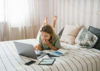 Woman Lying on Bed While Using a Laptop