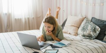 Woman Lying on Bed While Using a Laptop