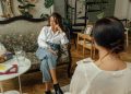 Woman in White Long Sleeve Shirt Sitting on Brown Wooden Chair