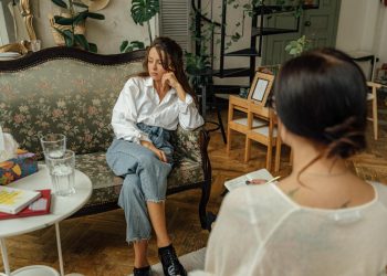 Woman in White Long Sleeve Shirt Sitting on Brown Wooden Chair