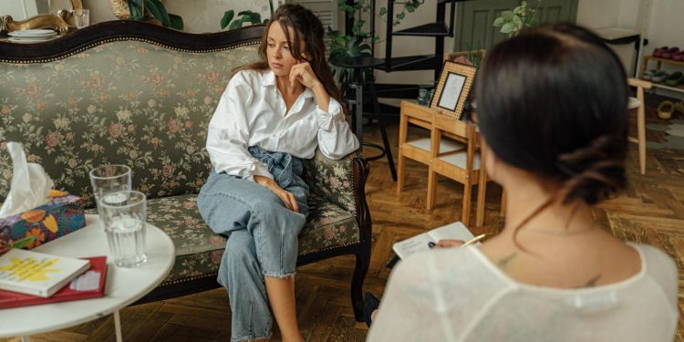 Woman in White Long Sleeve Shirt Sitting on Brown Wooden Chair