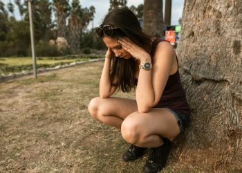 Photo of a Woman Crouching while Her Hands are on Her Head