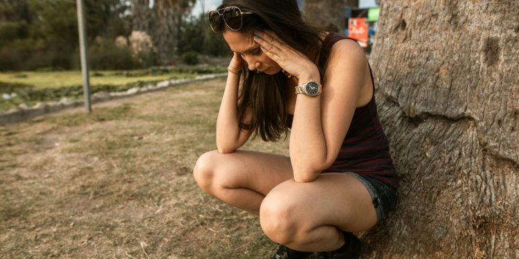 Photo of a Woman Crouching while Her Hands are on Her Head