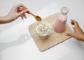 People taking dessert and glass bottle of milkshake placed on wooden board
