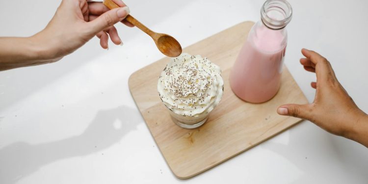 People taking dessert and glass bottle of milkshake placed on wooden board