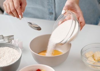 Person Pouring Powdered Sugar in a Bowl
