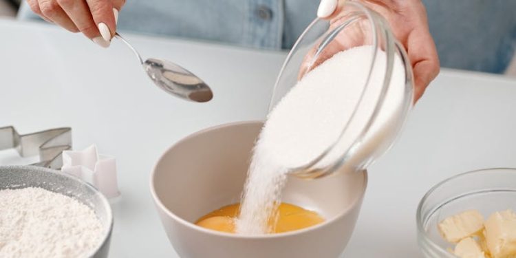 Person Pouring Powdered Sugar in a Bowl