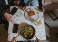 People Holding a Fork and Knife on the Table with Vegan Food