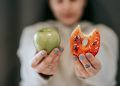 Woman showing apple and bitten doughnut