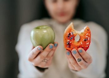 Woman showing apple and bitten doughnut