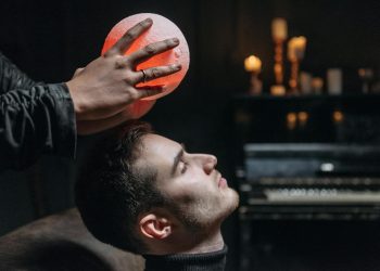 Person Holding an Illuminated Round Object on a Man's Forehead